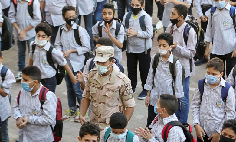 An army member wearing a protective mask stands guard between students as they attend the first day at Al Saadeya school, following months of closure due to the Covid-19 outbreak, Cairo, Egypt, 17 October 2020. Reuters, Mohamed Abd El Ghany.