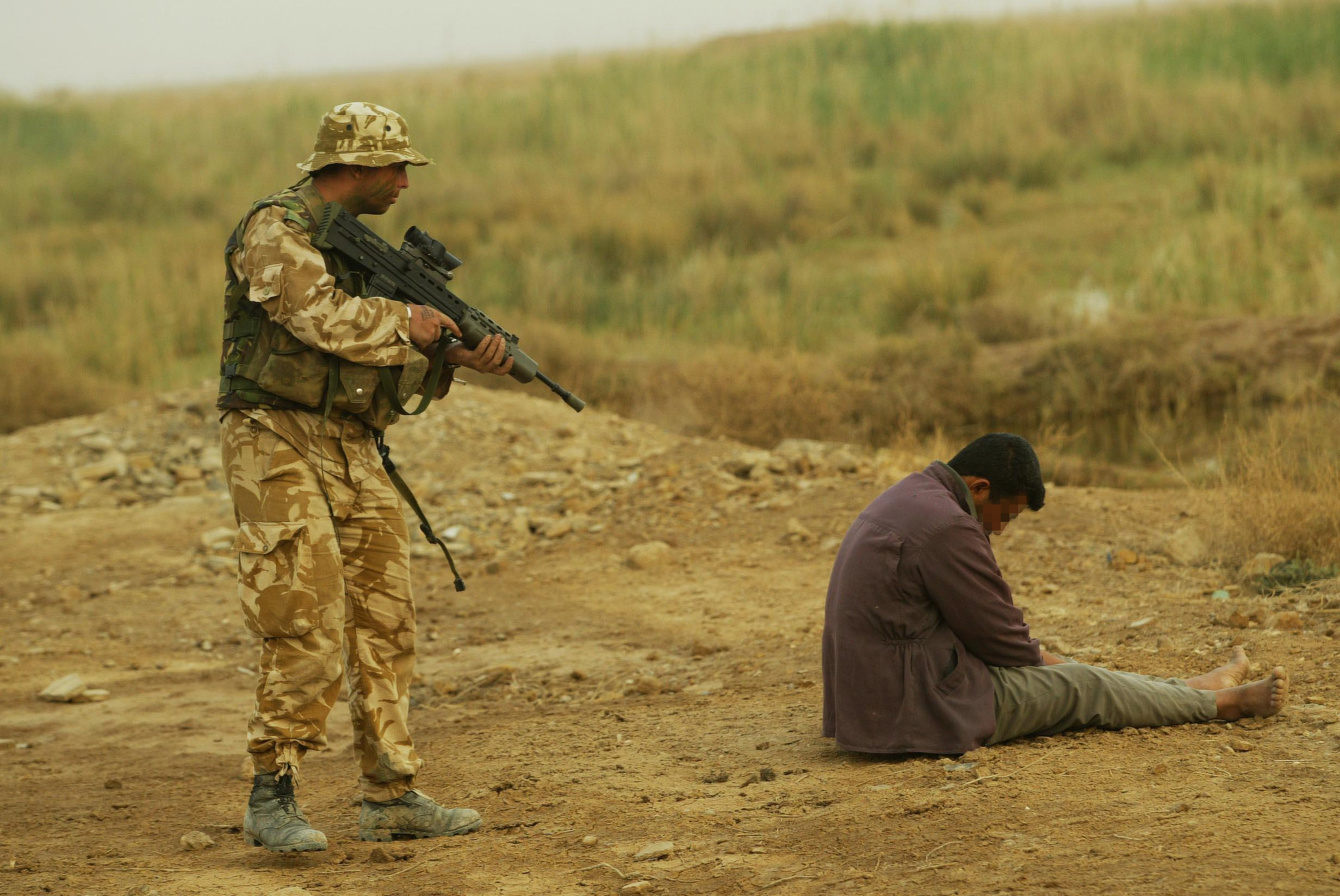 جندي من البحرية البريطانية يقف حراسة على عضو من حزب البعث، جنوب شرق البصرة، العراق، 26 مارس 2003. بي آيه إيميدجز عبر رويترز.