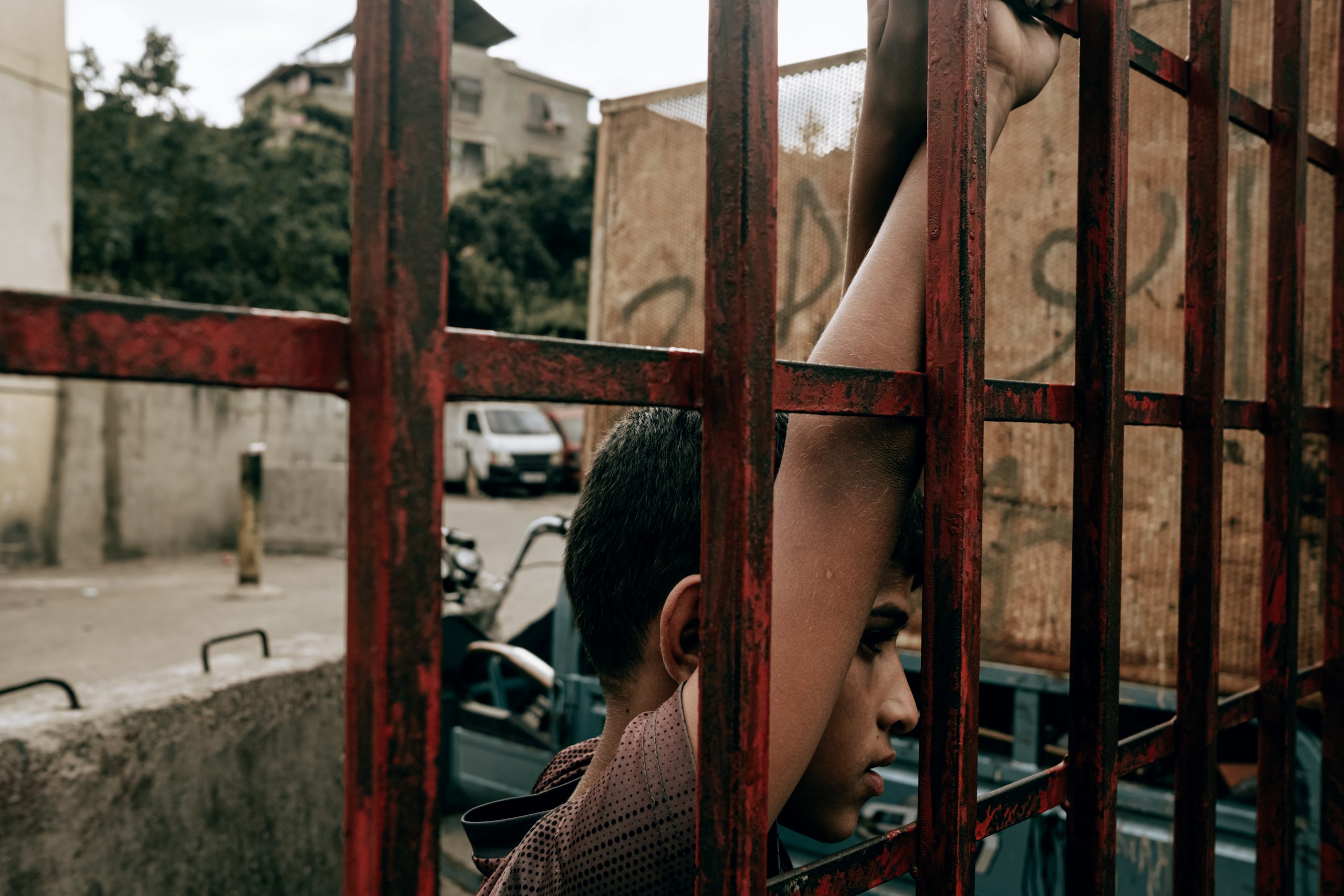 A young boy watches a soccer game, while standing behind bars, Shatila, Beirut, Lebanon. 11 October 2020. Karine Pierre, Agence Hans Lucas, via Reuters.