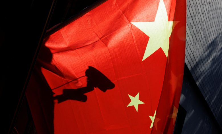 ظل كاميرا للمراقبة يظهر خلف العلم الصيني في بكين، الصين، 3 نوفمبر 2022. رويترز، توماس بيتر.
